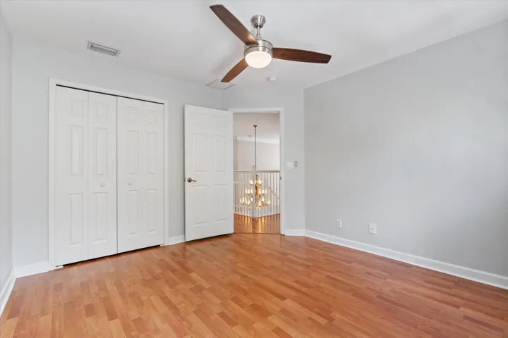 Wood-finish flooring, ceiling fan with integrated lighting, white trim, and bi-fold closet doors
