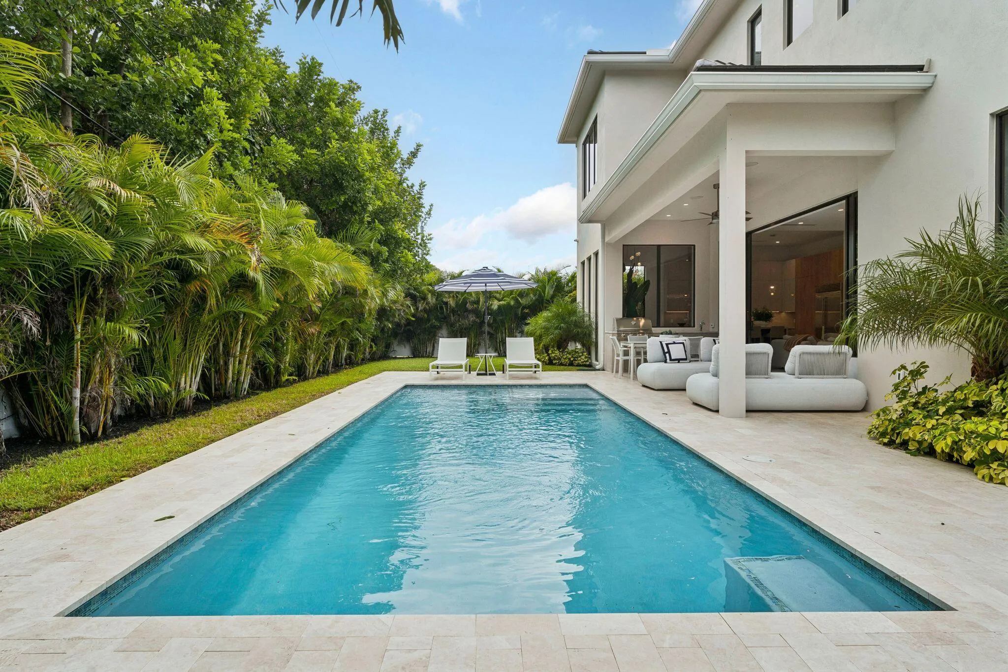 Rectangular swimming pool with integrated steps, surrounded by light-toned paving