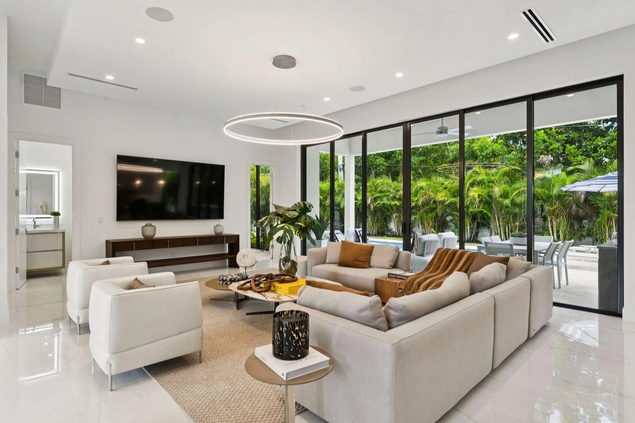 Spacious living area featuring polished tile flooring, recessed lighting, and a contemporary circular chandelier