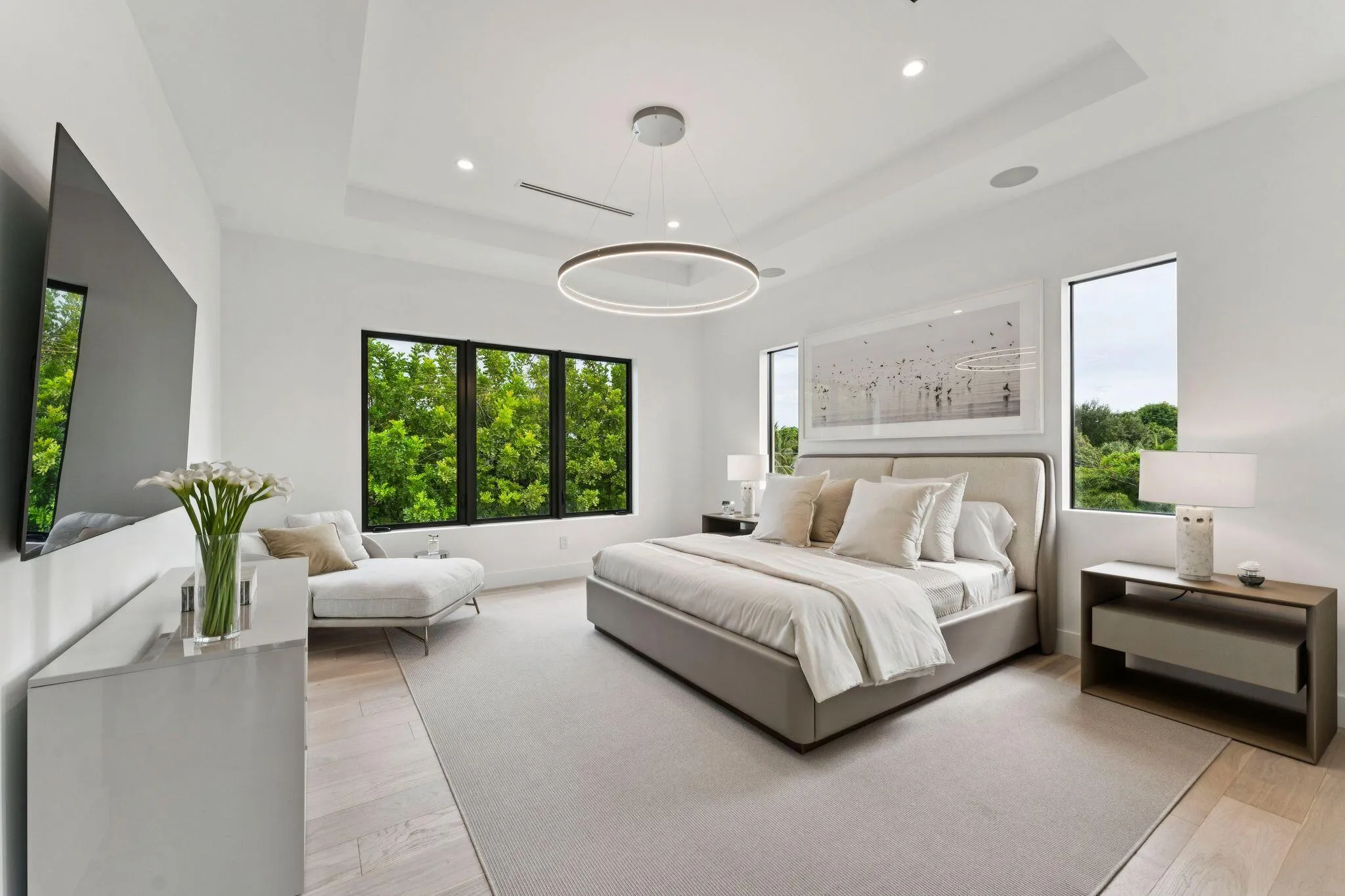 Recessed lighting, light wood-finish flooring, tray ceiling, and large windows with black frames