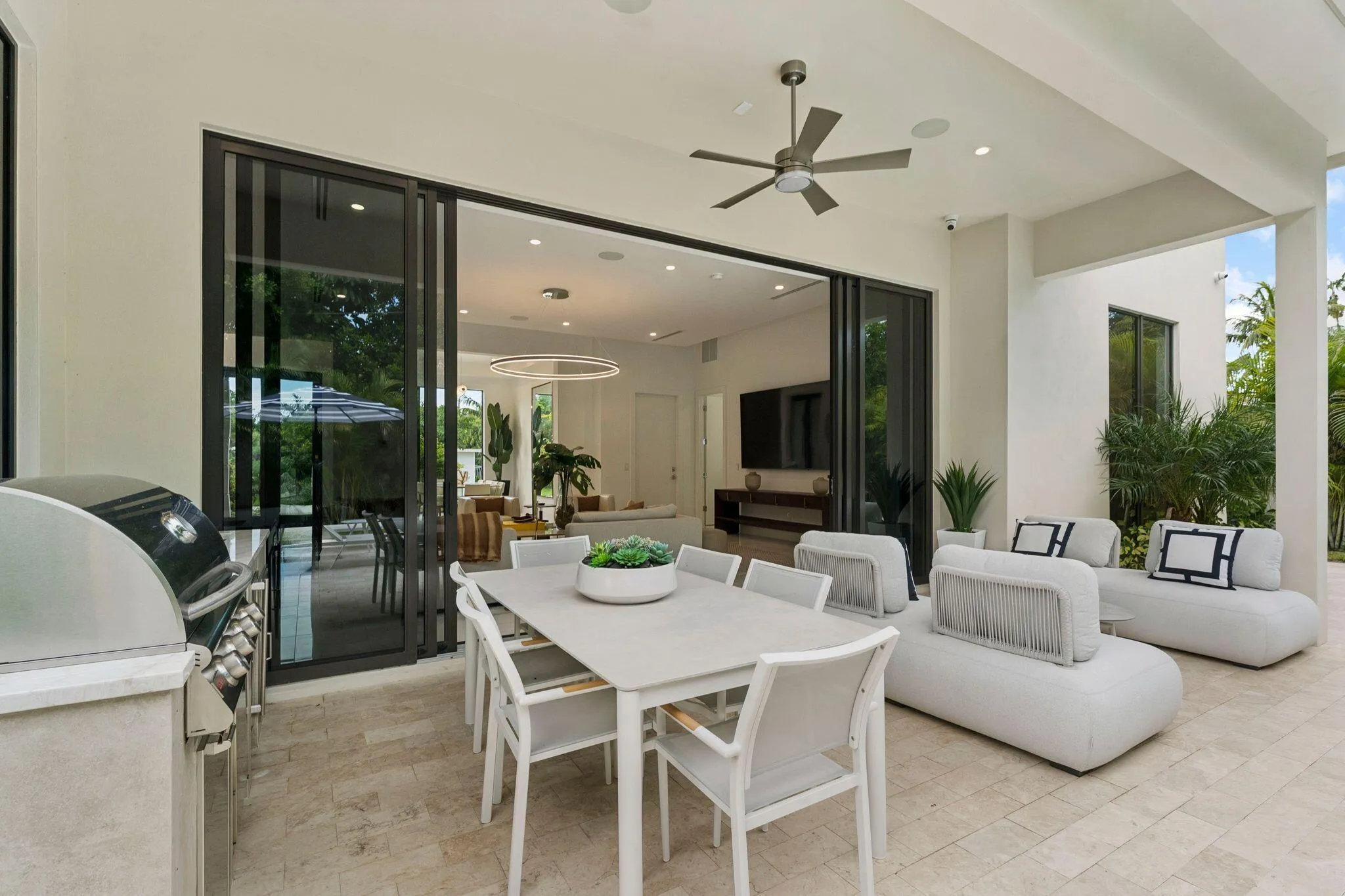Covered patio with large format tile flooring, a built-in outdoor grill station, and a ceiling fan
