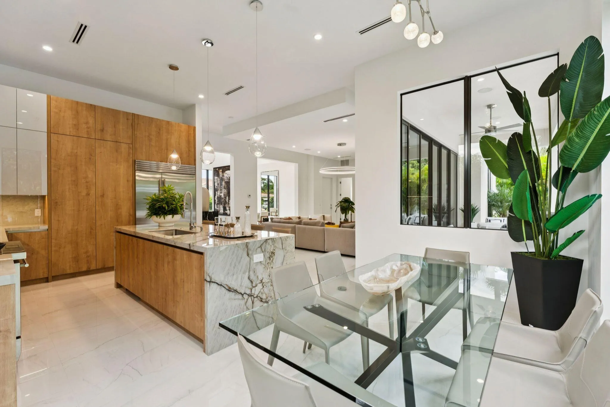 Gourmet kitchen featuring wood-finish cabinetry, a large waterfall island with integrated sink, and pendant lighting