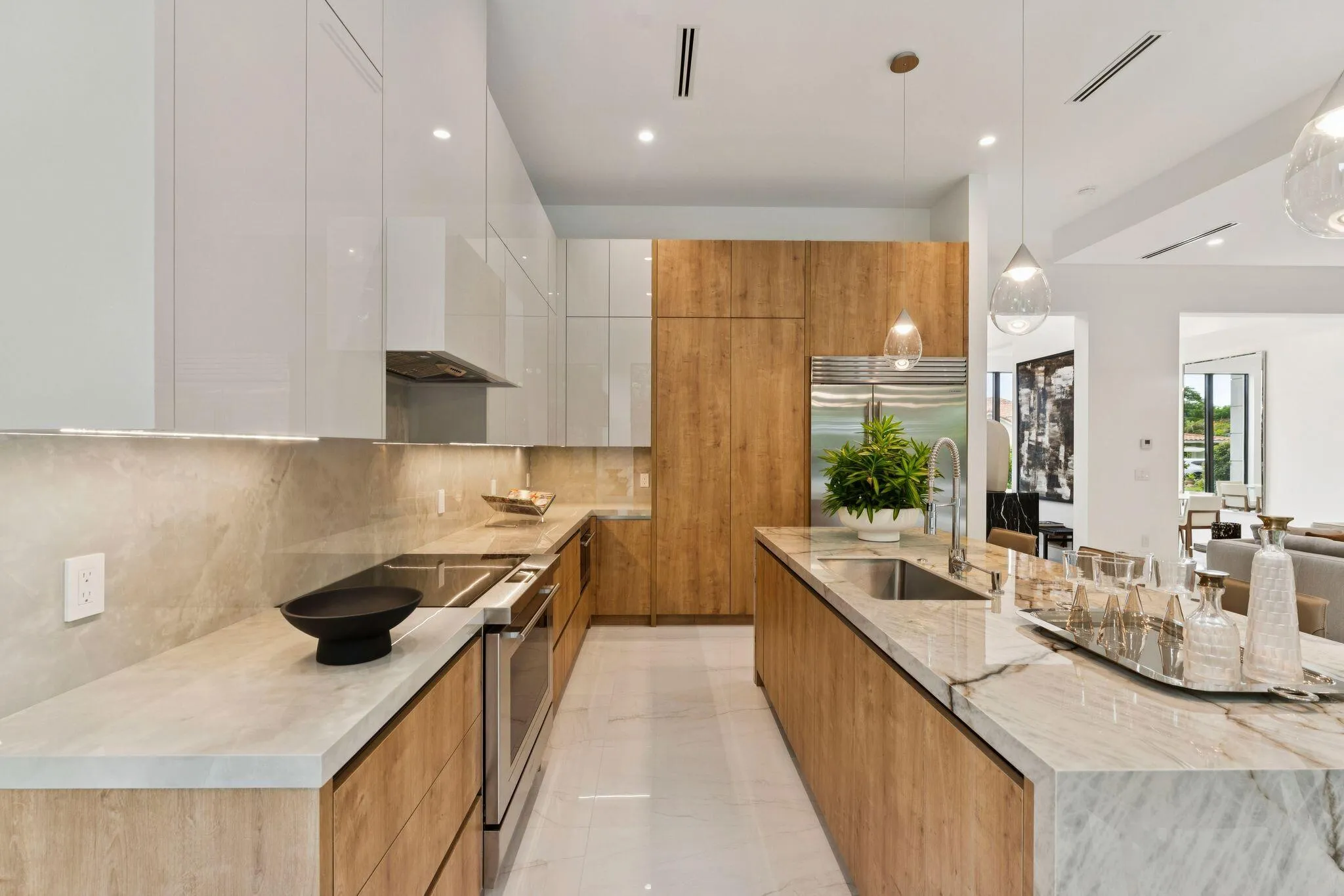Contemporary kitchen featuring wood-finish cabinetry, white upper cabinets, integrated stainless steel appliances, a kitchen island with an undermount sink, and recessed lighting