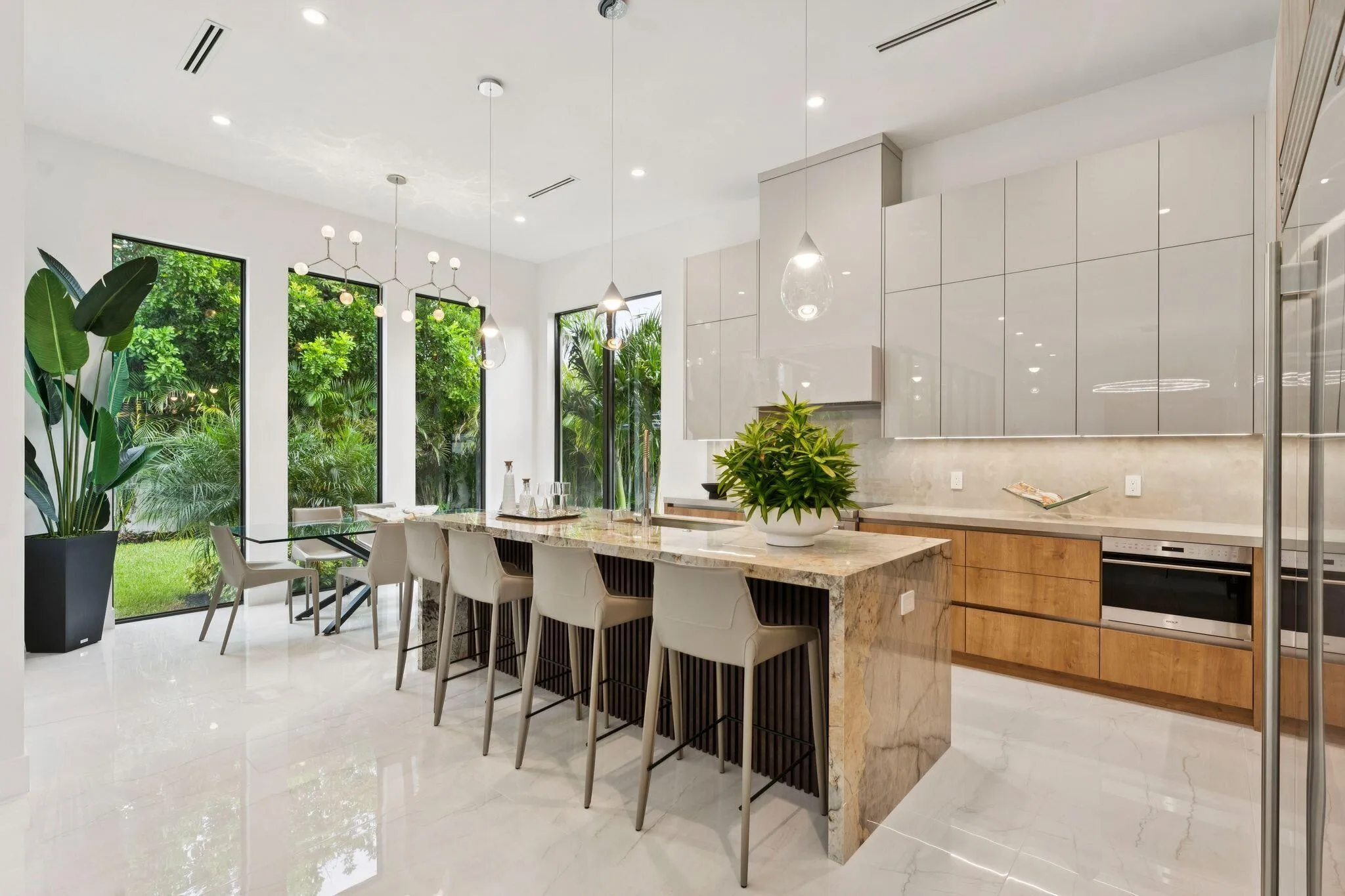 Modern kitchen featuring an expansive center island, integrated oven, glossy flat-panel cabinetry, and wood-finish lower cabinetry