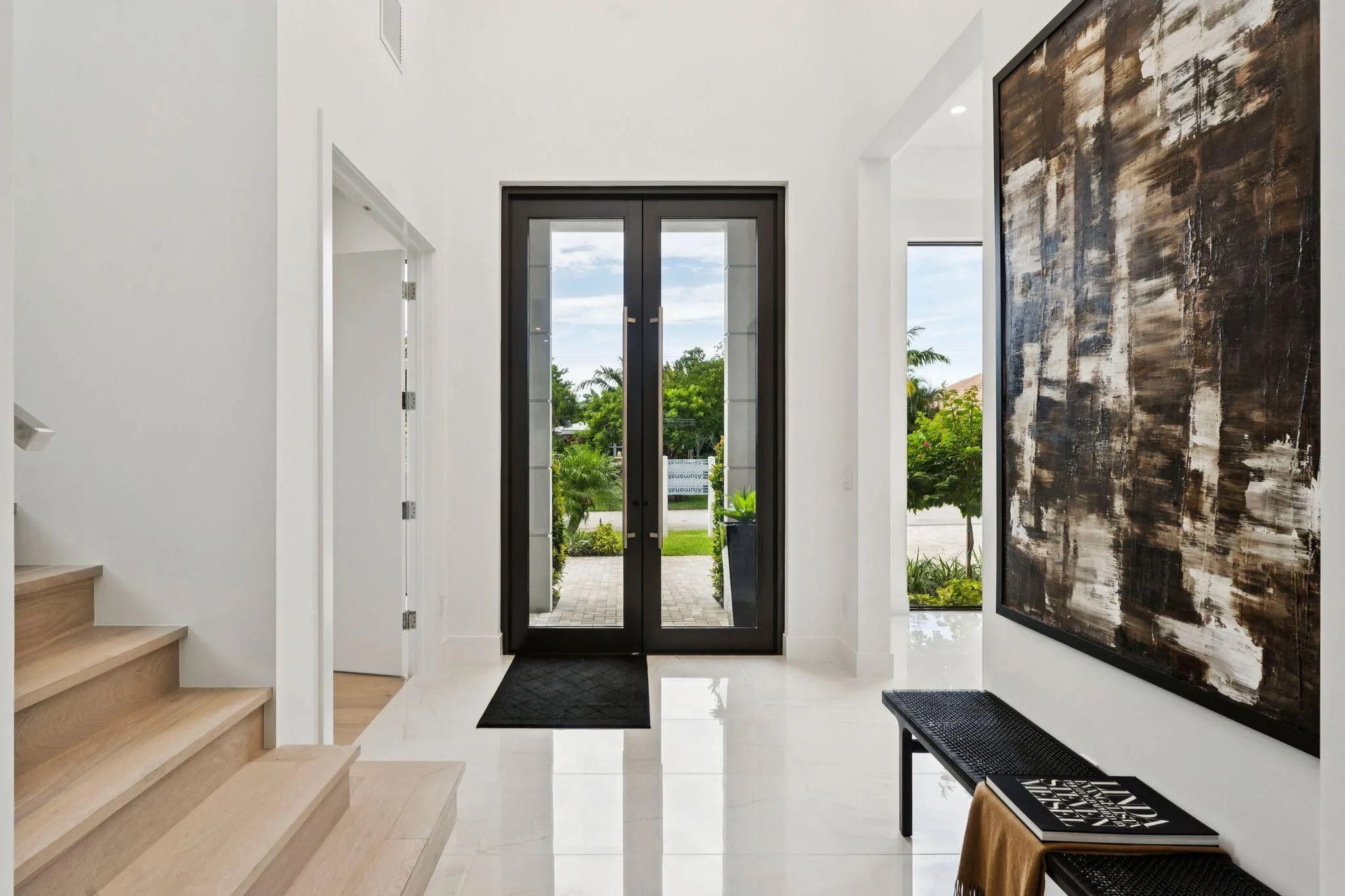 Entryway featuring double glass-paneled doors, wood-finish staircase, and polished tile flooring