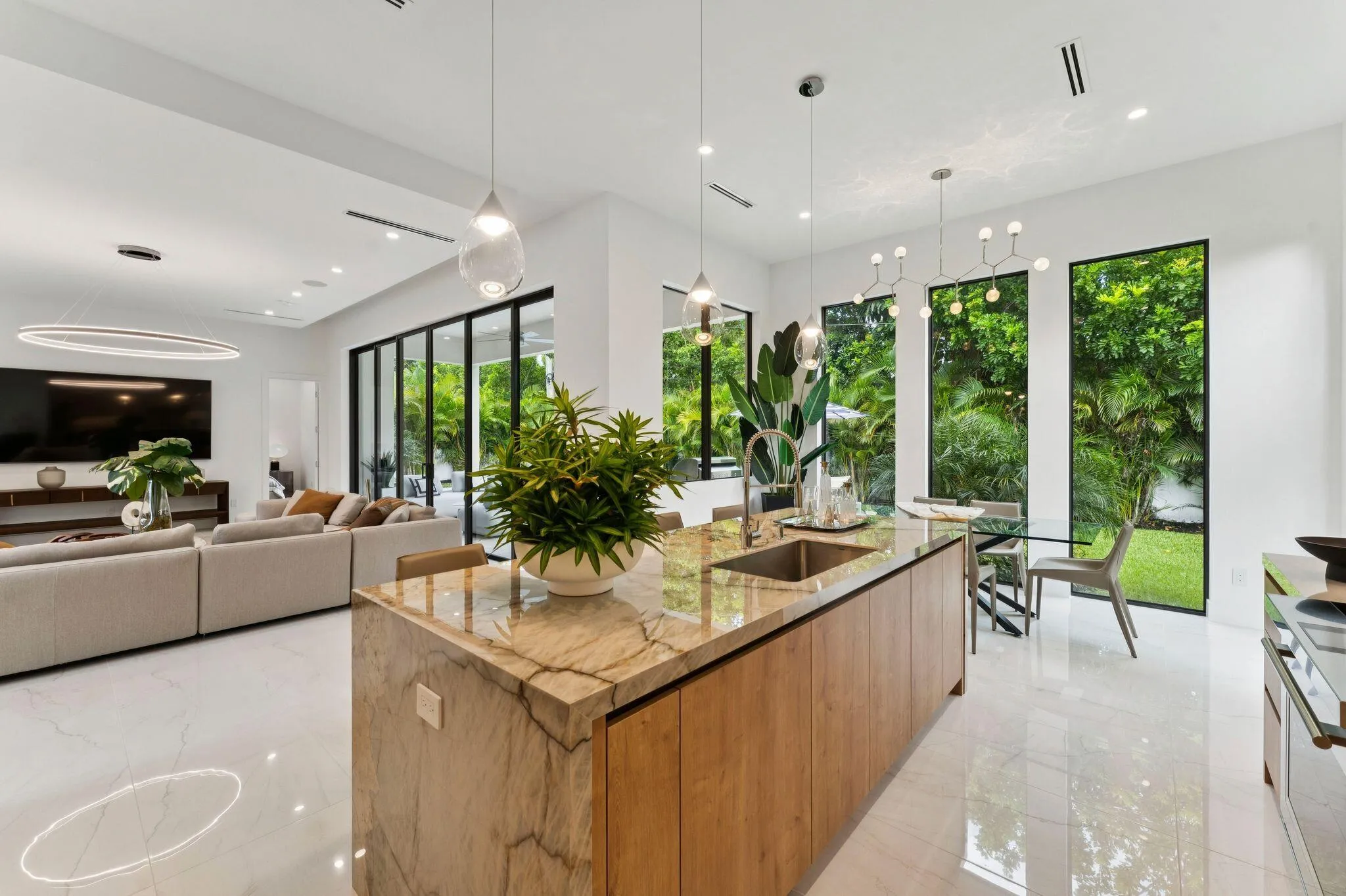 Expansive open-concept space featuring high ceilings, white tile flooring, and a large kitchen island with integrated sink