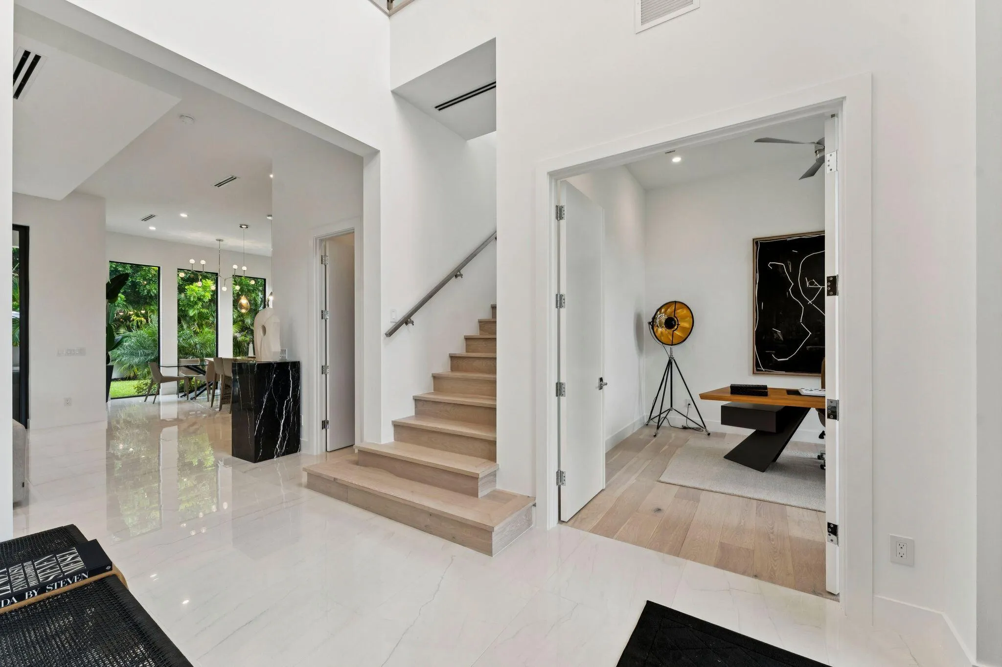 Polished tile flooring, a built-in staircase with a metal handrail, and high ceilings