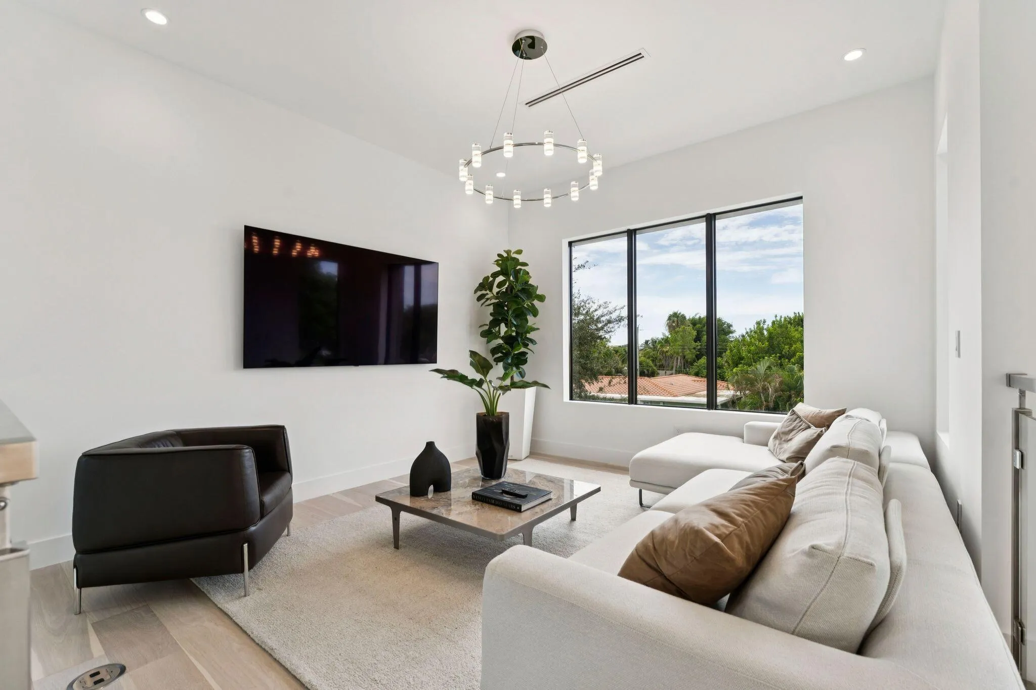 High ceilings, recessed lighting, and a contemporary chandelier illuminate this living area