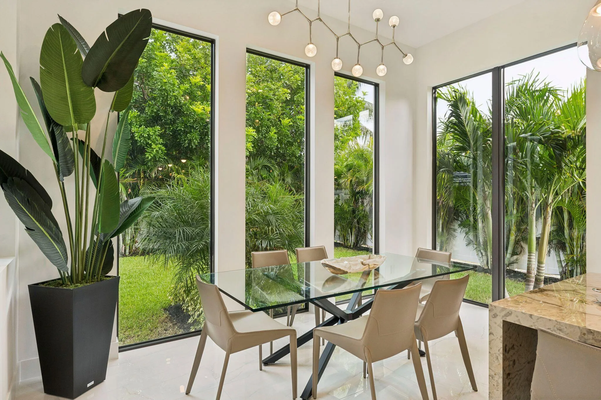 Tall windows with black frames, white walls, light tile flooring, and a contemporary chandelier
