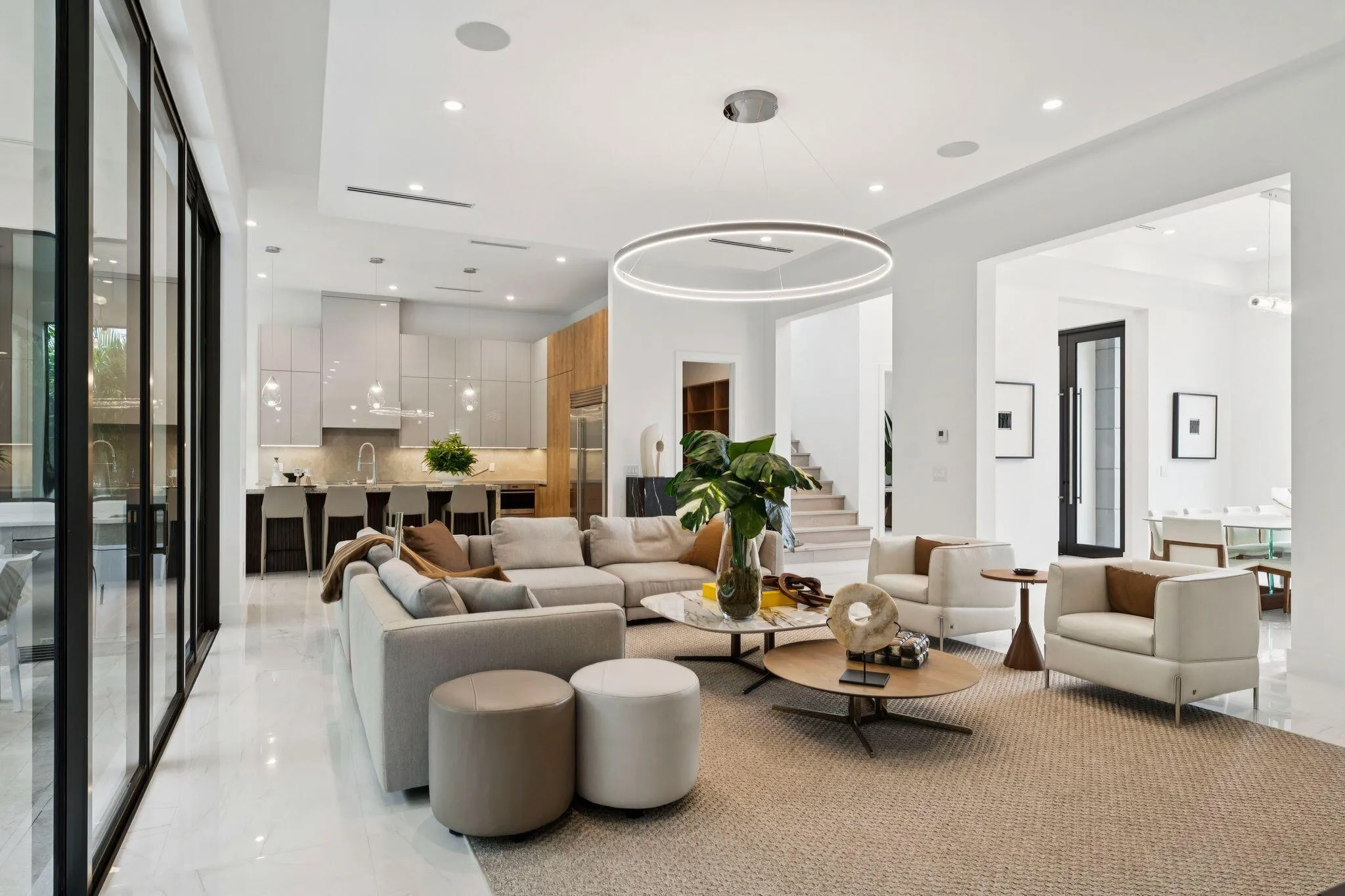 Open-concept living space featuring polished light-finish flooring, recessed and pendant lighting, and expansive glass sliding doors