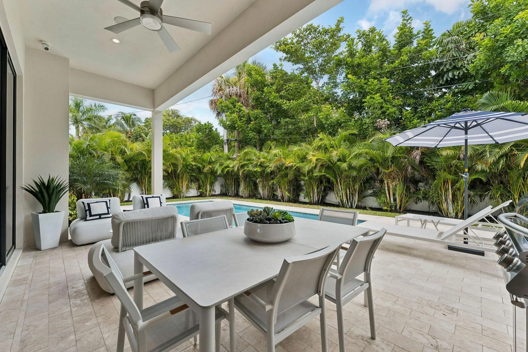 Expansive covered patio with recessed lighting and a ceiling fan, featuring a private swimming pool, tiled patio flooring, and lush landscaping