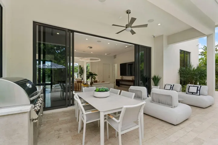 Covered patio with large format tile flooring, a built-in outdoor grill station, and a ceiling fan