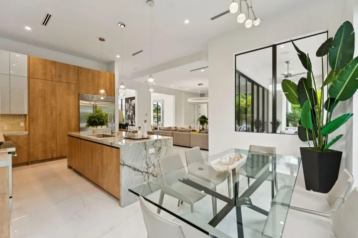 Gourmet kitchen featuring wood-finish cabinetry, a large waterfall island with integrated sink, and pendant lighting