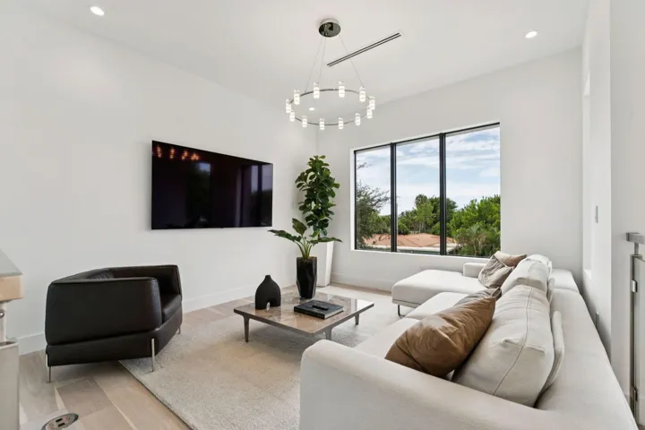 High ceilings, recessed lighting, and a contemporary chandelier illuminate this living area