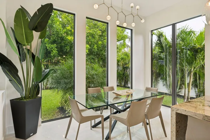 Tall windows with black frames, white walls, light tile flooring, and a contemporary chandelier