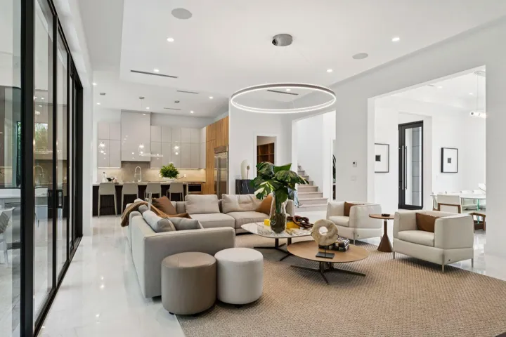 Open-concept living space featuring polished light-finish flooring, recessed and pendant lighting, and expansive glass sliding doors