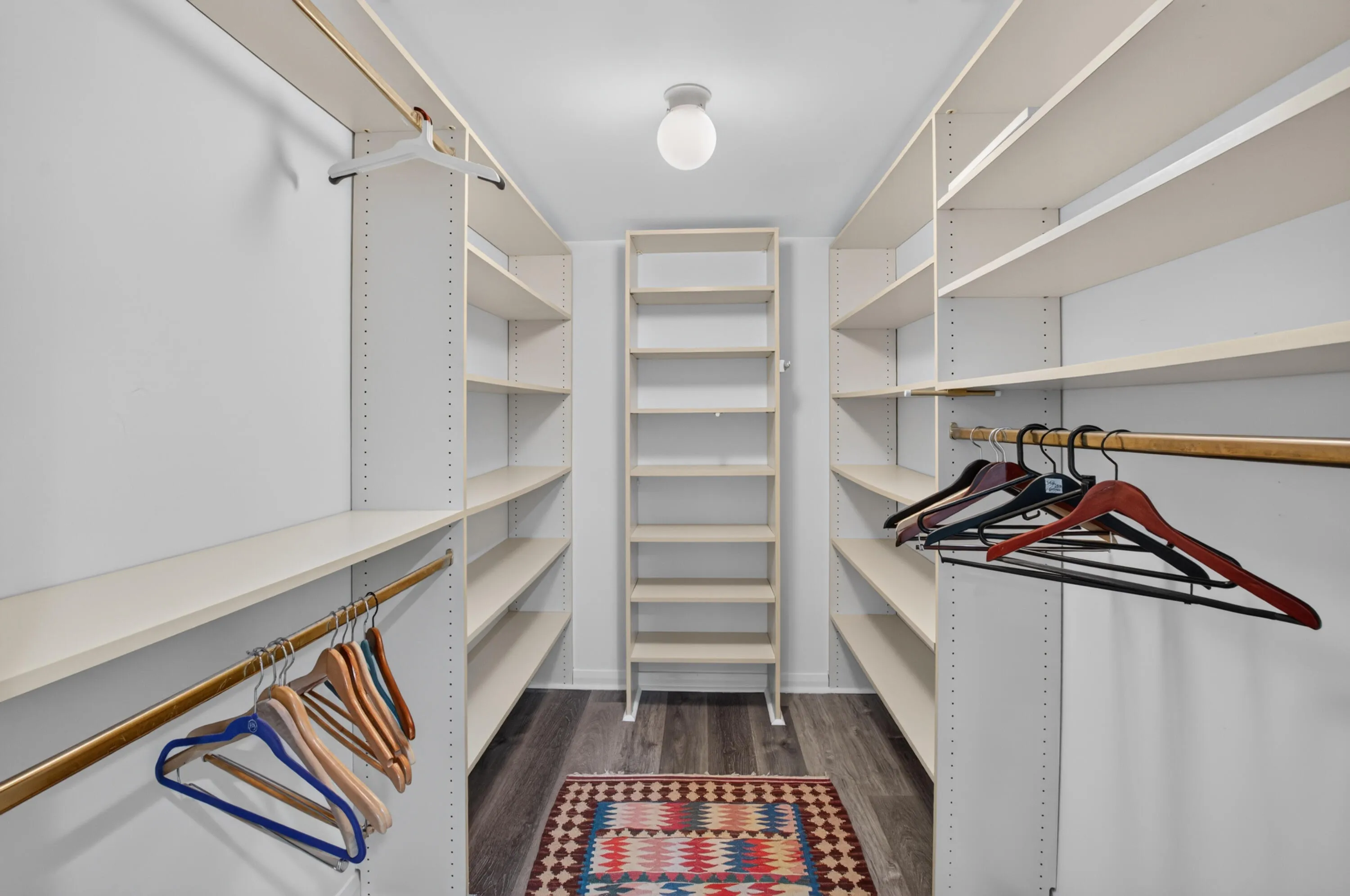 Walk-in closet featuring built-in shelving, hanging rods, and wood-finish flooring