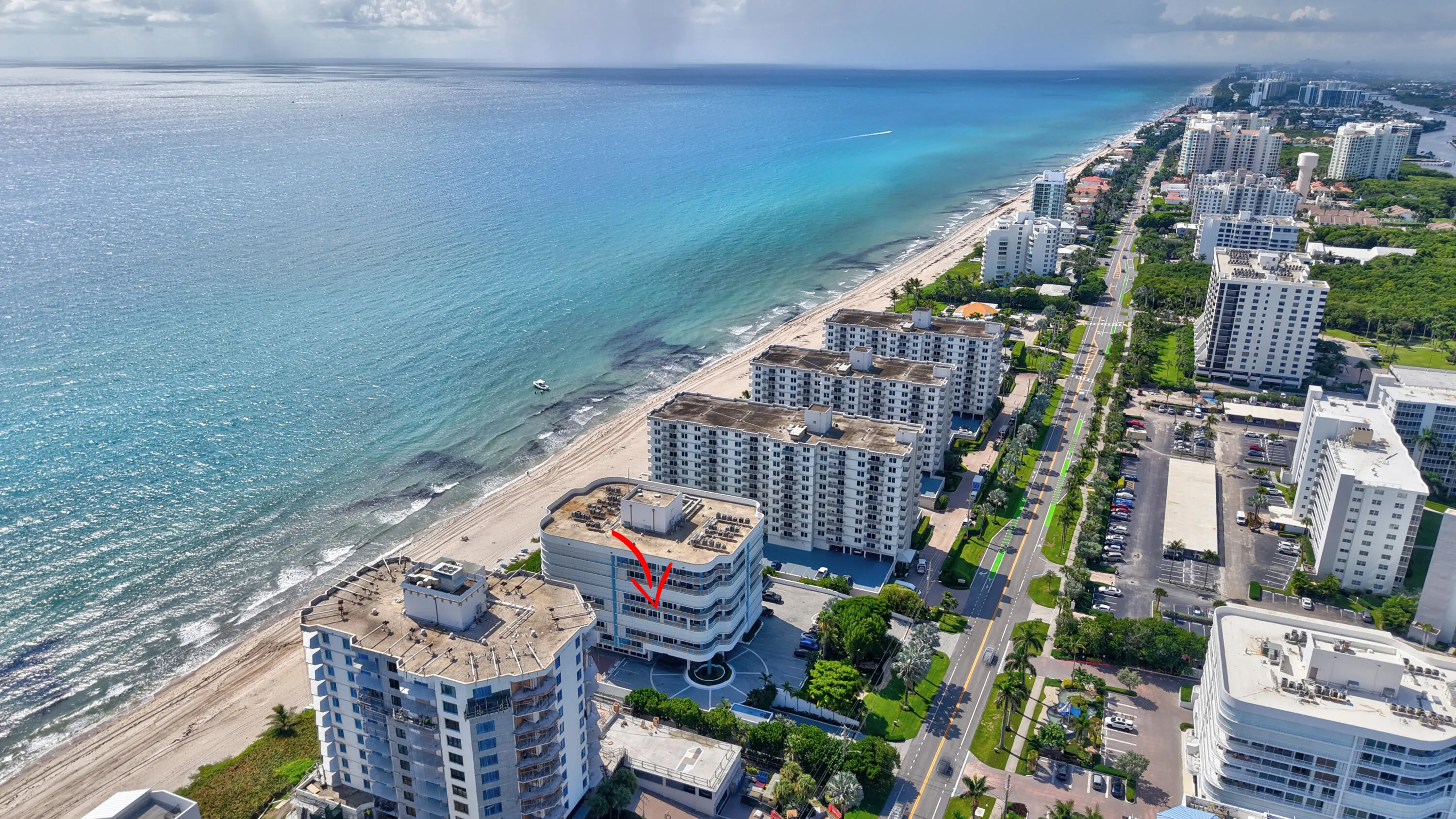 Coastal high-rise architecture with direct beach access, proximity to a major roadway, and extensive coastline