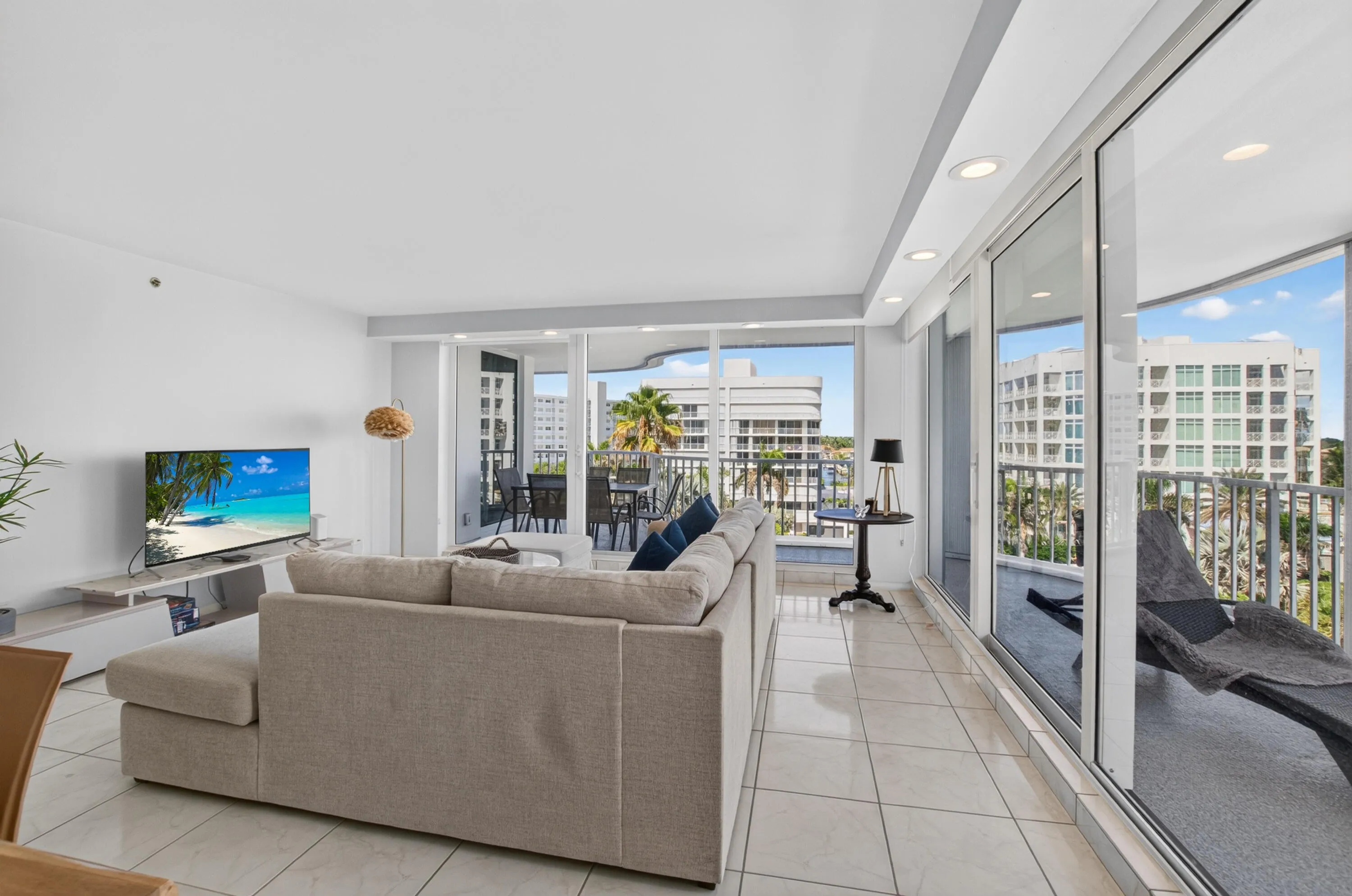 Tiled flooring throughout, recessed lighting, and expansive glass sliding doors accessing a private balcony with a metal railing