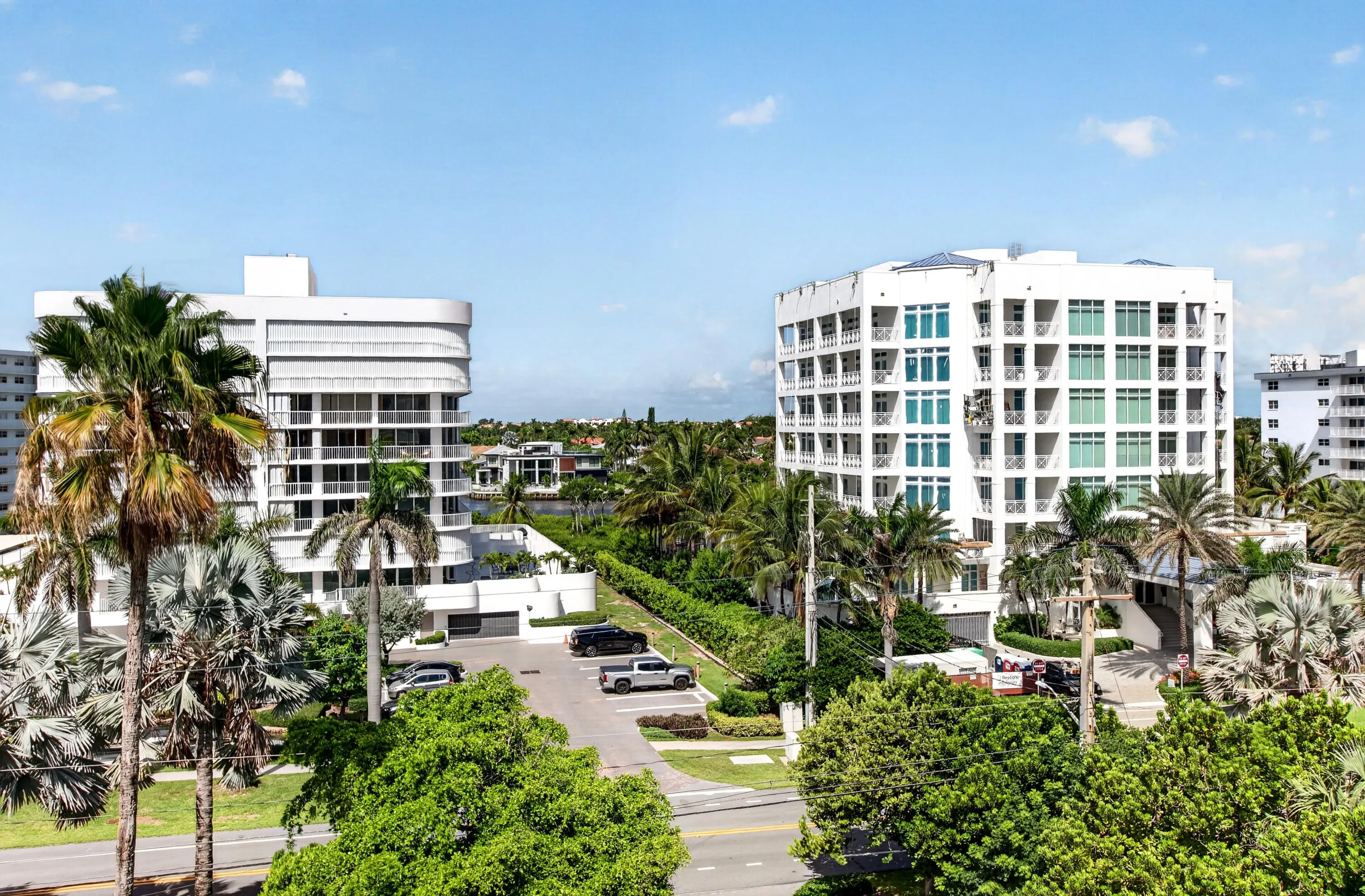 Modern high-rise architecture with expansive windows, multiple balconies, and a surrounding of mature tropical landscaping