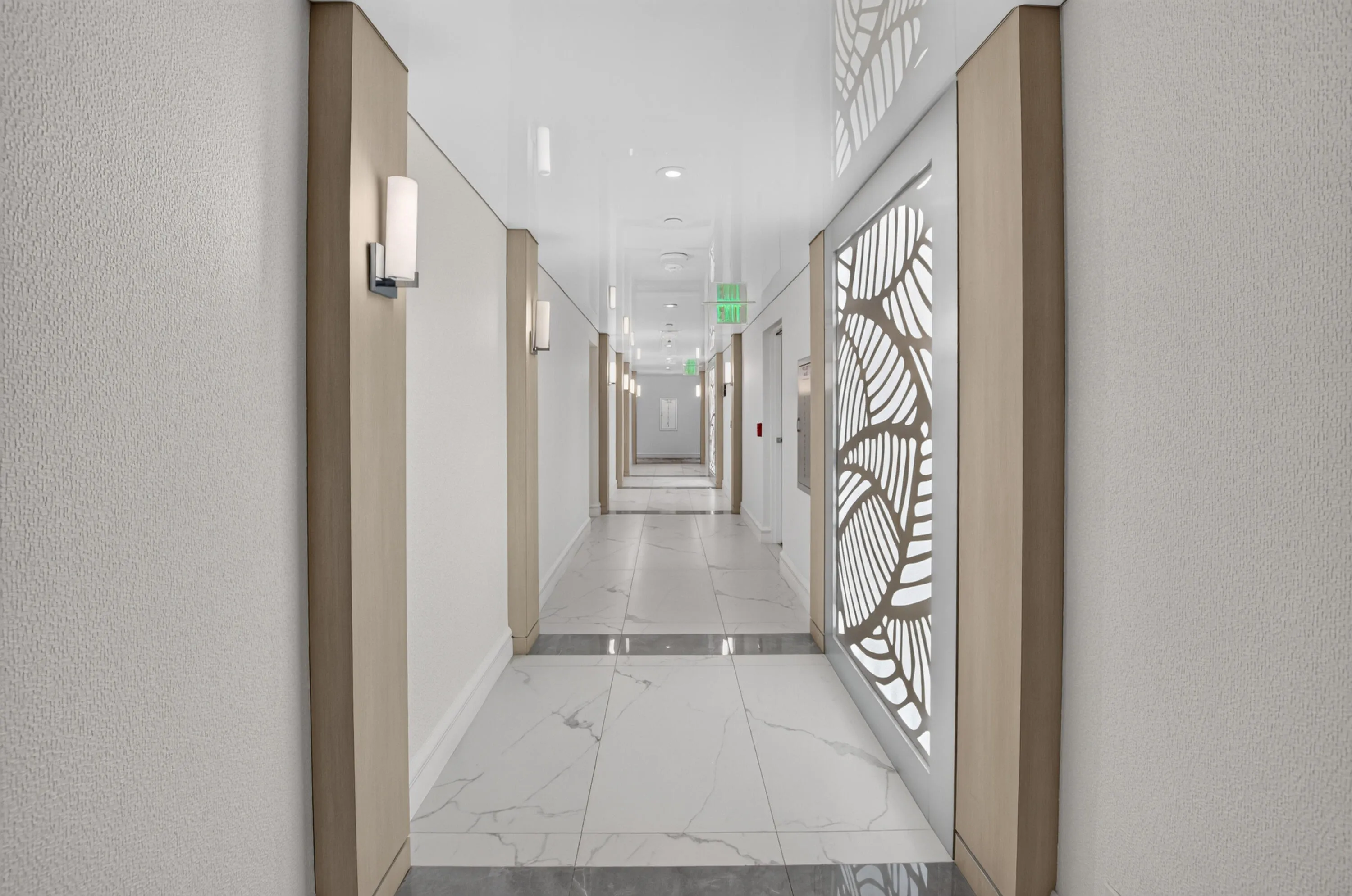 Corridor featuring sconce lighting, decorative wall panels, and high-gloss ceiling