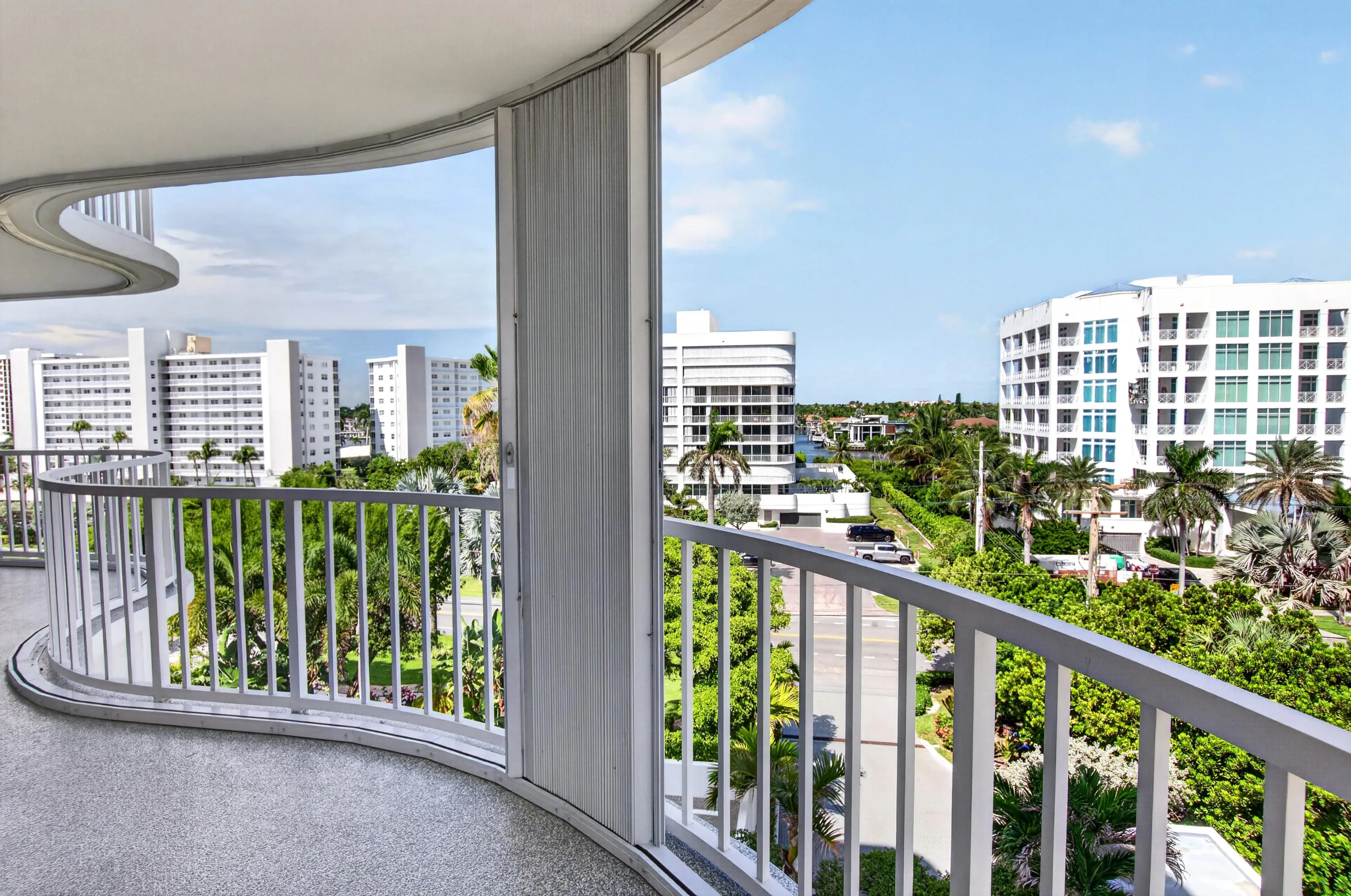 Curved balcony with a speckled concrete floor and white metal railing