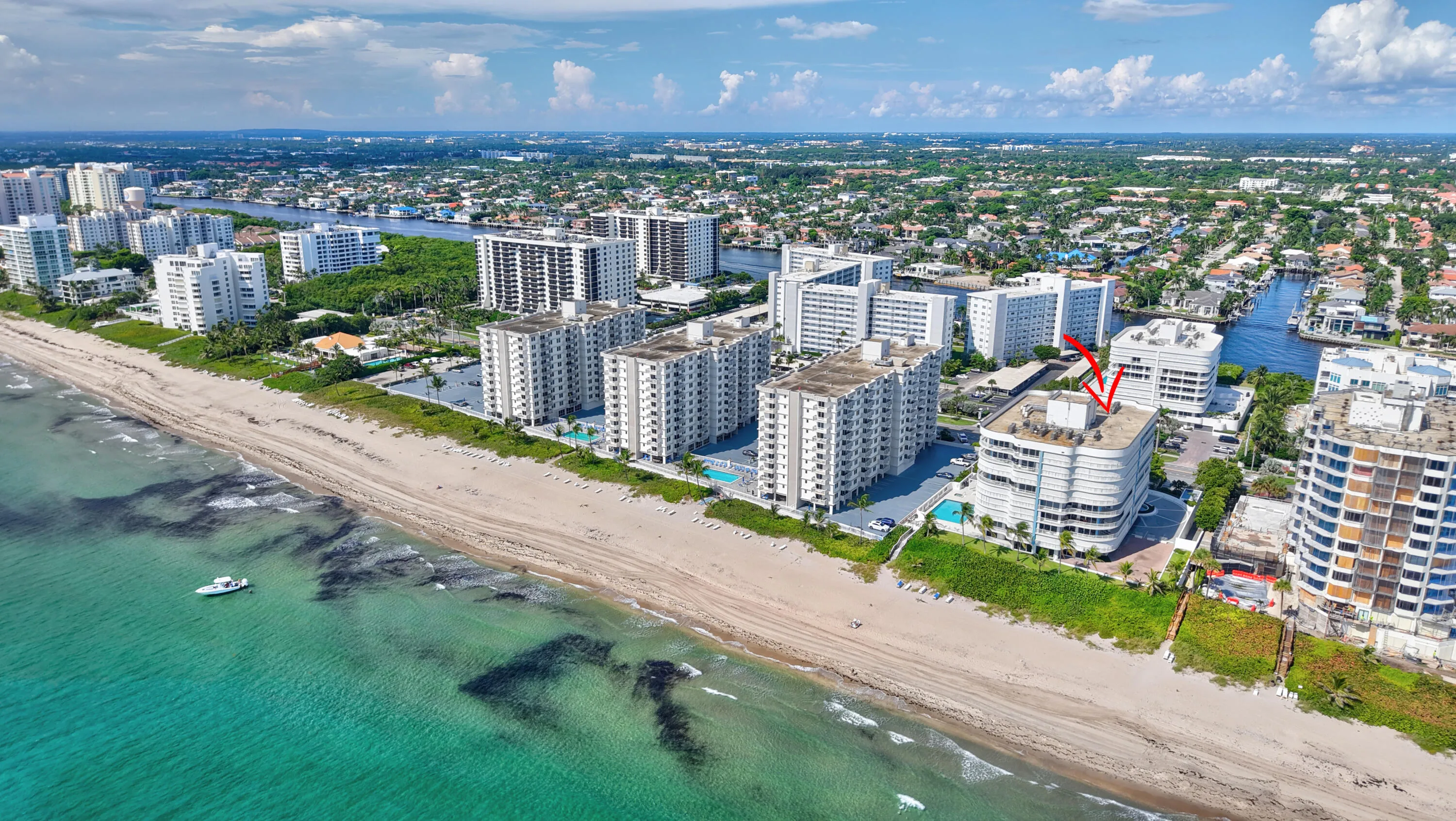 Coastal building with beach access, featuring a rooftop structure, adjacent canal system, and surrounding urban landscape