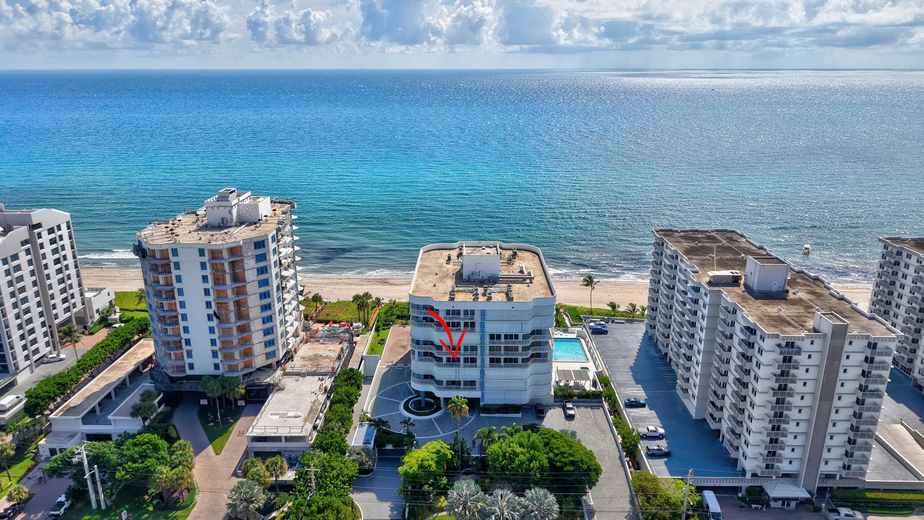 Oceanfront building featuring multiple balconies, a circular drive with a central fountain, and an outdoor swimming pool