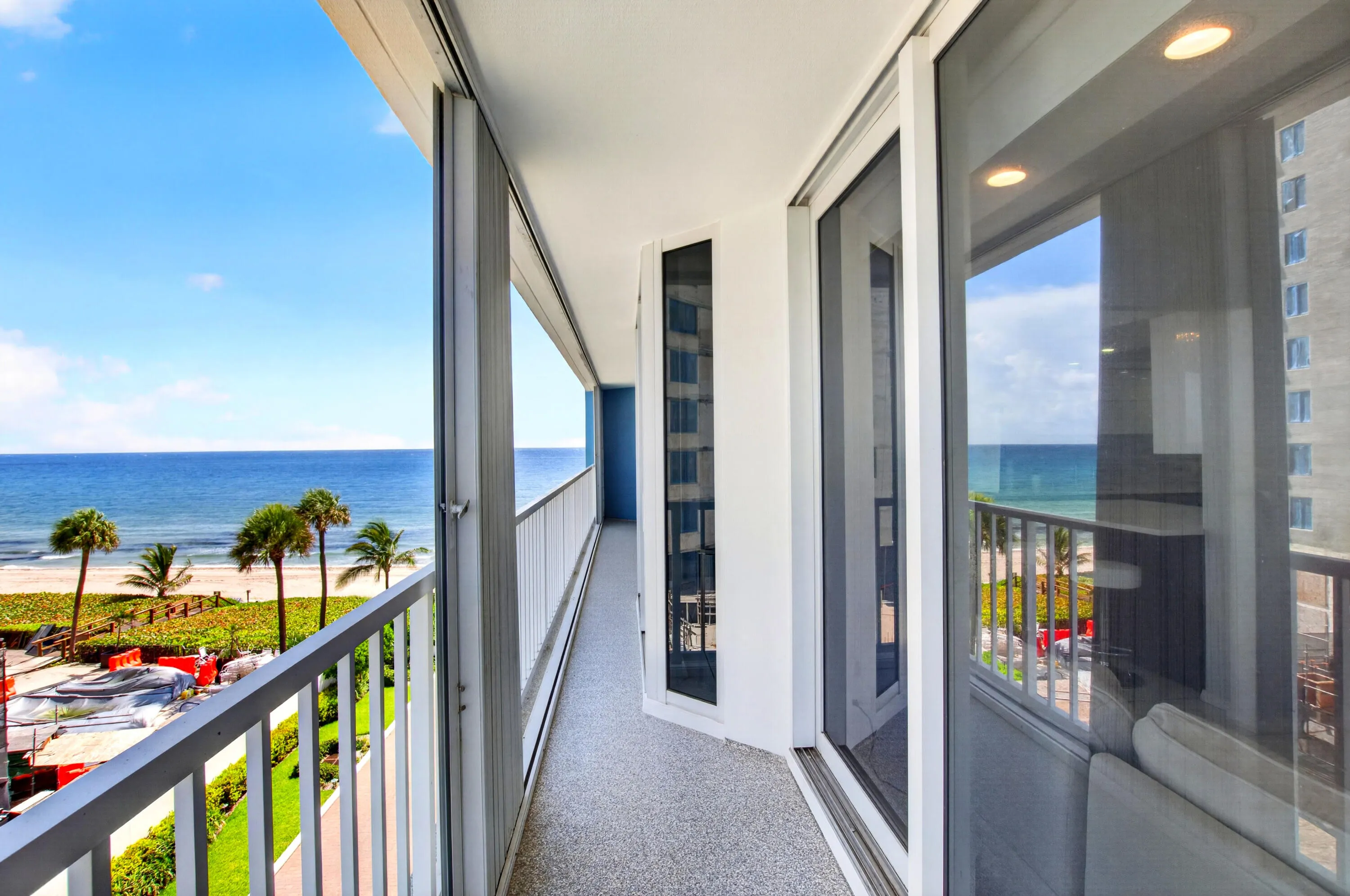Private balcony with an expansive beachfront landscape, a white railing, and sliding glass doors