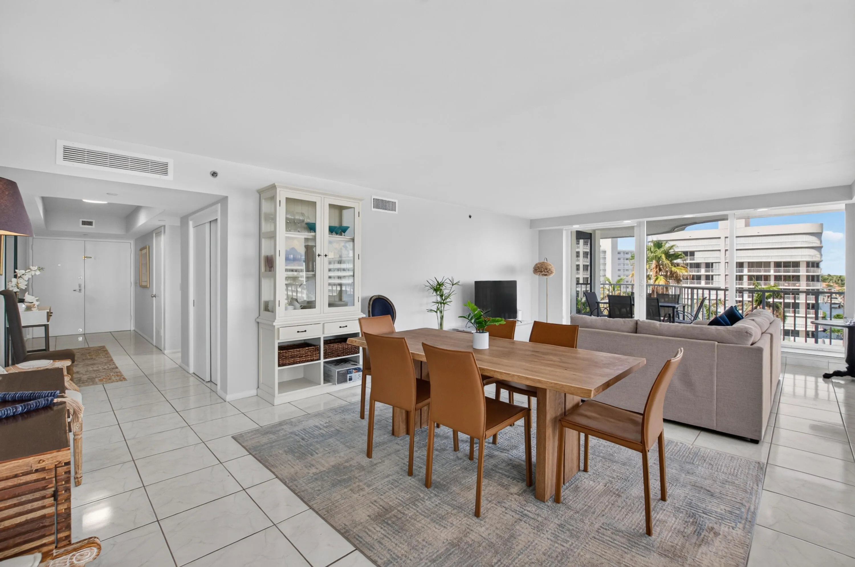 Expansive living area with large format tile flooring, a dining area, and a built-in hutch