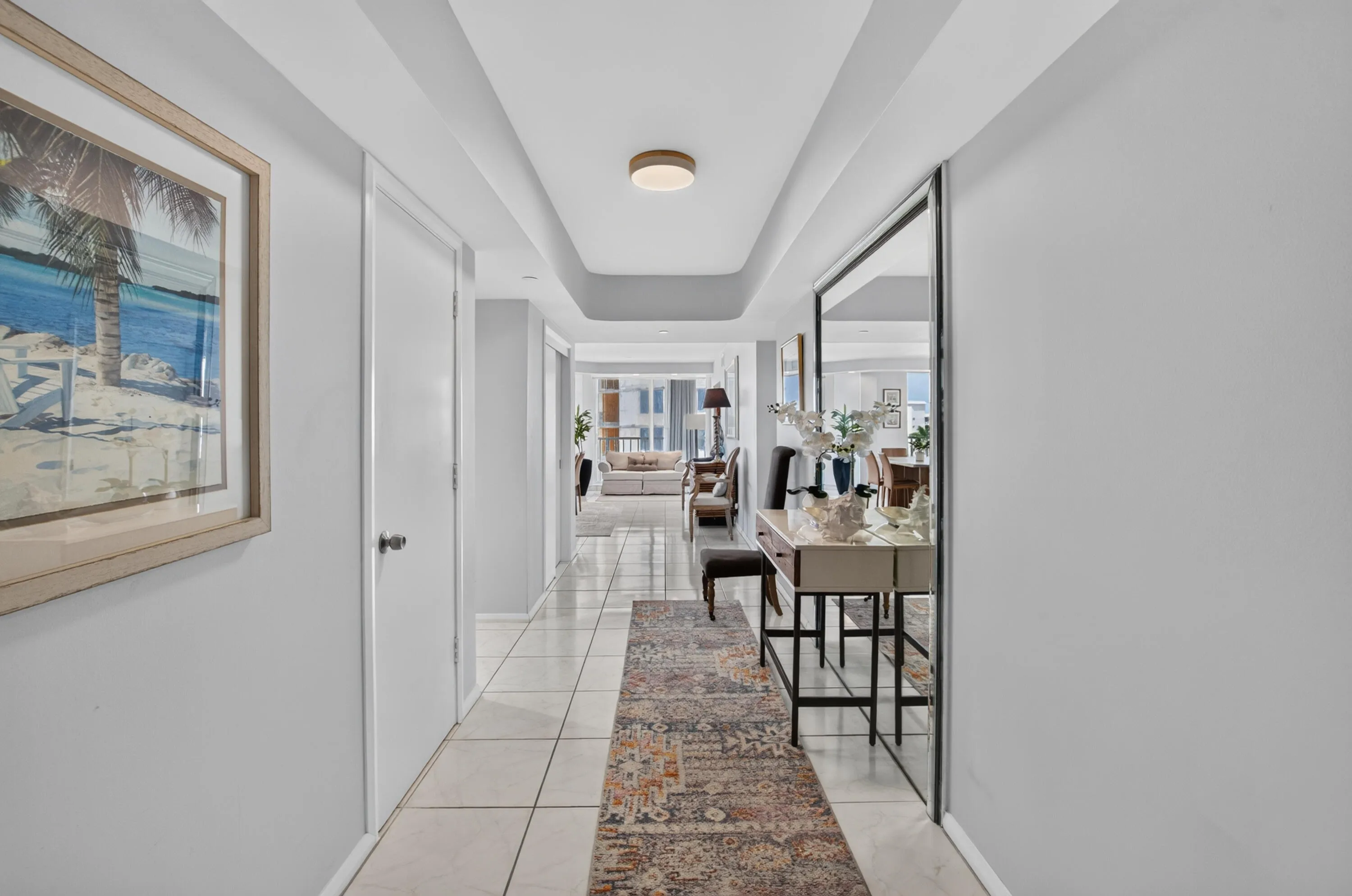 Recessed ceiling with integrated lighting, large format tile flooring, and a full-length mirrored wall