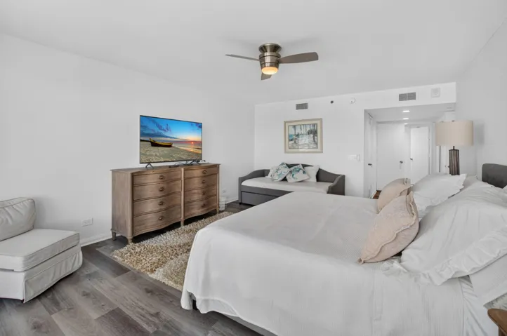 Wood-finish flooring with white walls and a ceiling fan with integrated lighting