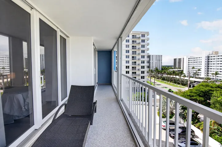 Outdoor balcony with white railings, textured flooring, and large sliding glass panels