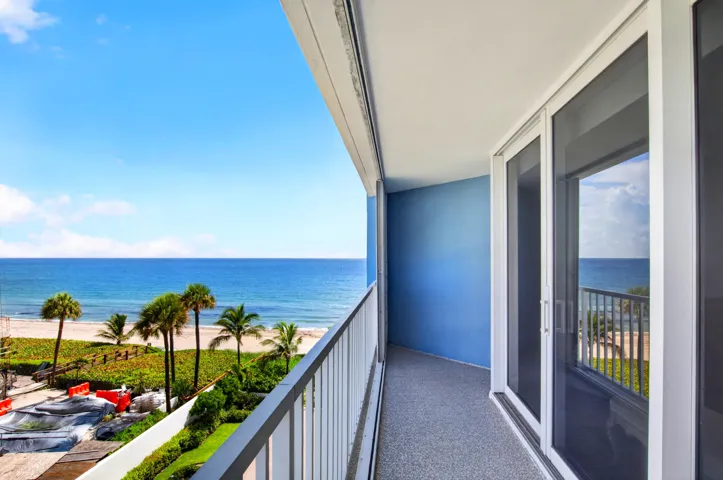Balcony with expansive oceanfront scenery, white railings, blue exterior wall, and sliding glass doors