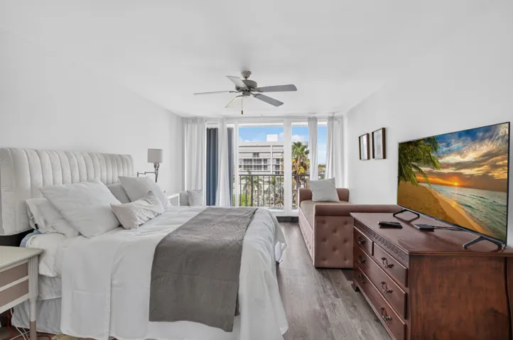 Wood-finish flooring, ceiling fan, and sliding glass doors to a balcony