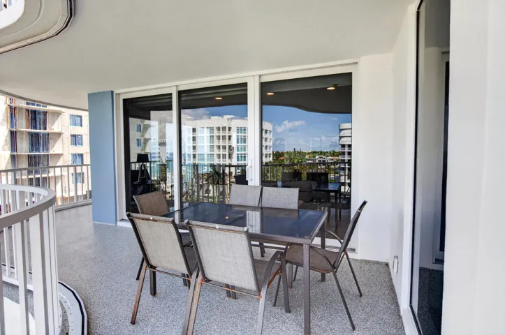 Balcony featuring a speckled flooring surface, white railing, and sliding glass doors