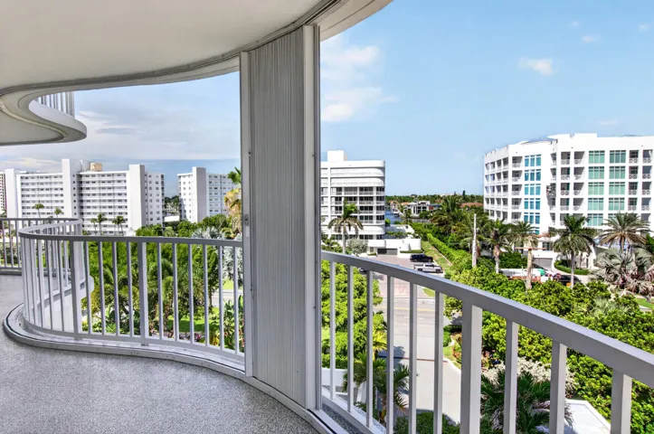 Curved balcony with a speckled concrete floor and white metal railing