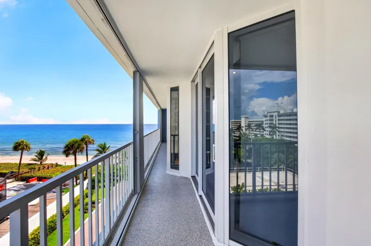 Outdoor balcony with ocean backdrop, gray railing, and textured flooring