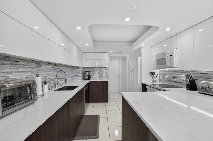 U-shaped kitchen with white flat-panel cabinetry and dark wood-finish base cabinets