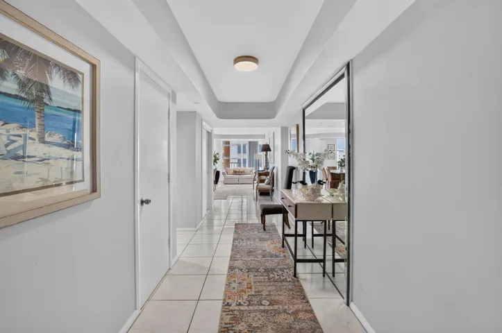 Recessed ceiling with integrated lighting, large format tile flooring, and a full-length mirrored wall