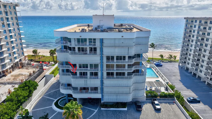 Coastal high-rise architecture with expansive balconies, a ground-level swimming pool, and direct beach access