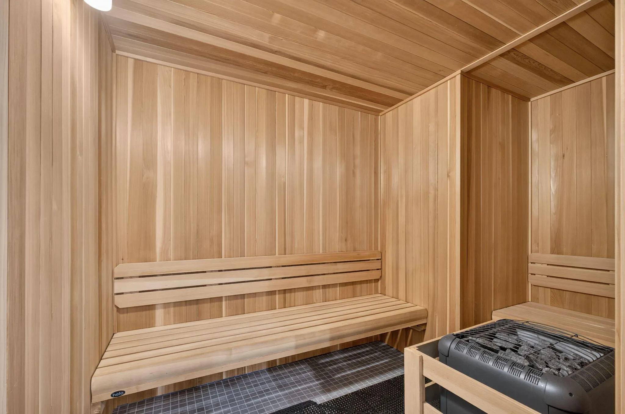 Wood-paneled sauna featuring multiple wooden benches and a built-in electric heater