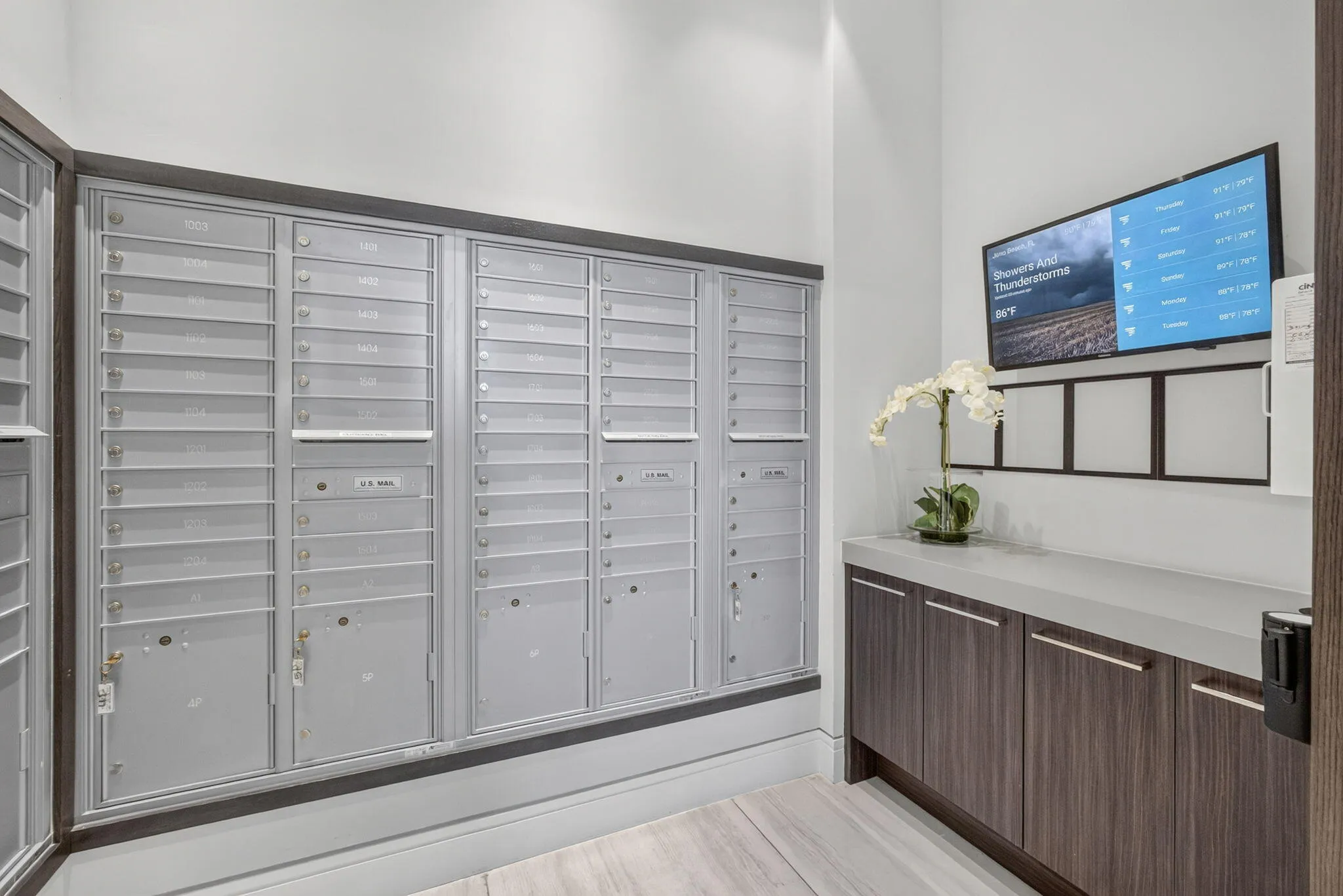 Catch up on the days news while picking up your mail just off thel lobby on your way to the elevaor. Wall-mounted mailboxes with a wood-finish base, integrated cabinetry, and a light-colored countertop