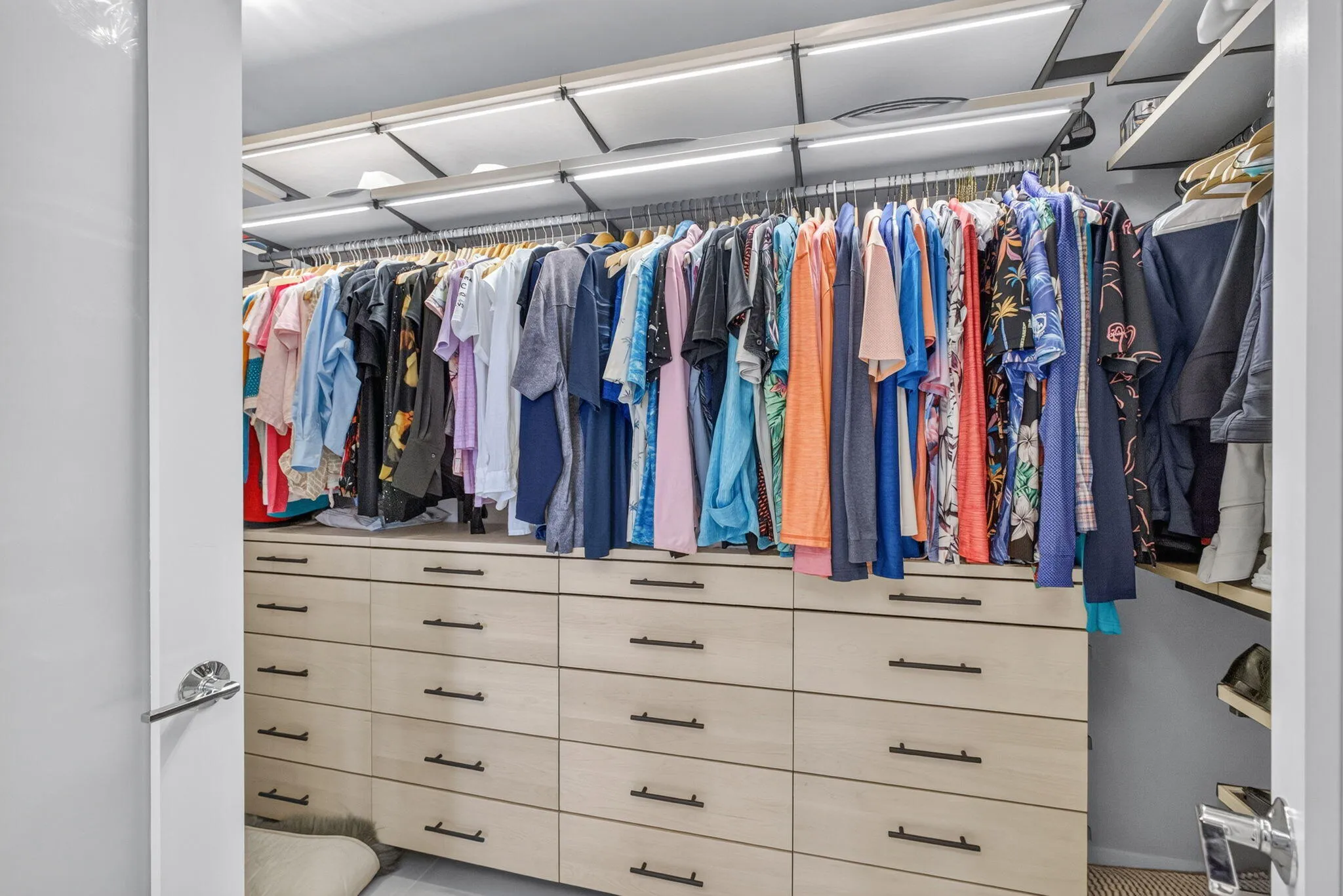 CUSTOM Built-in closet system featuring multiple wood-finish drawers, integrated hanging rods, and recessed overhead lighting