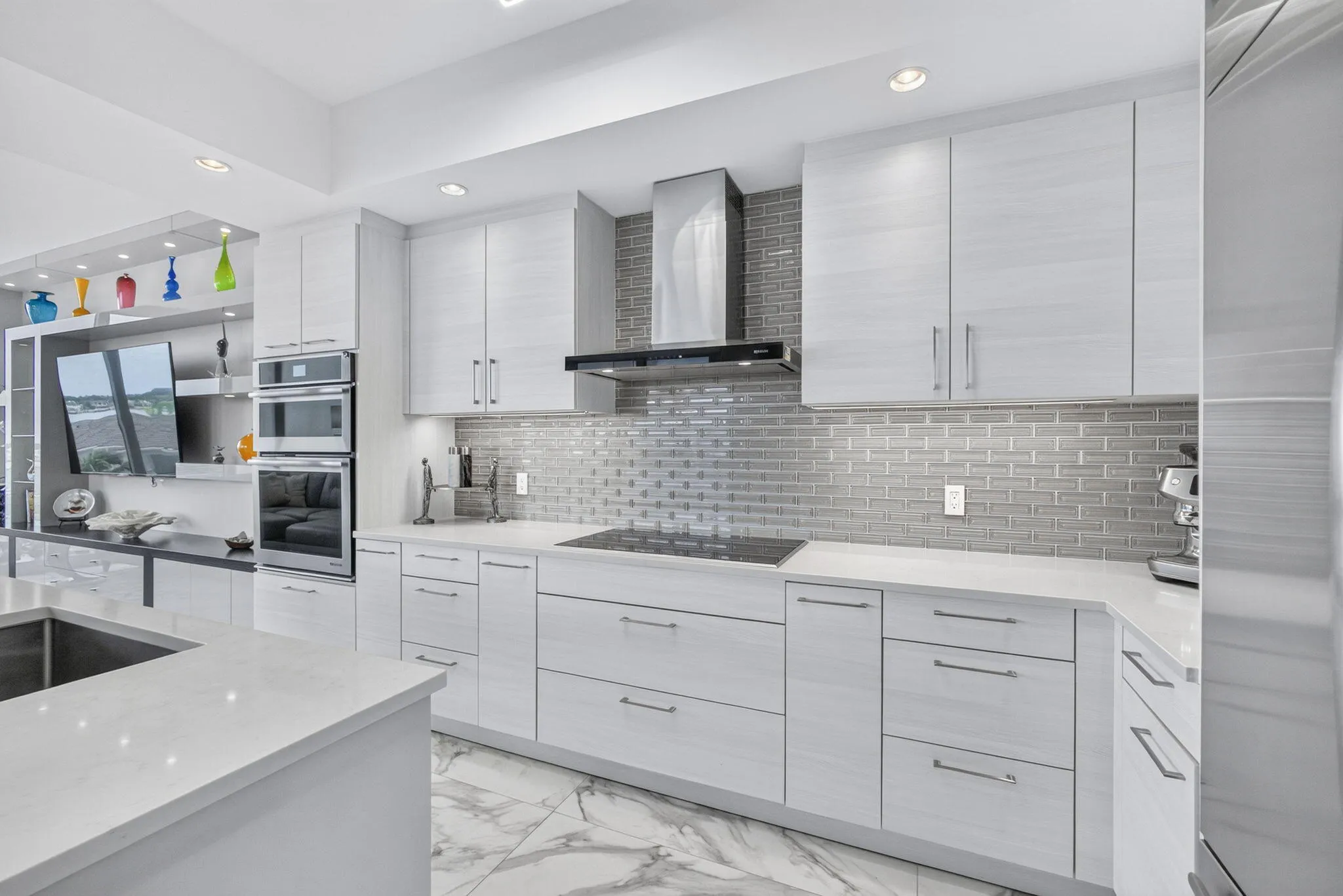 Sleek kitchen featuring light-toned cabinetry, a subway tile backsplash, and integrated High-end stainless steel appliances