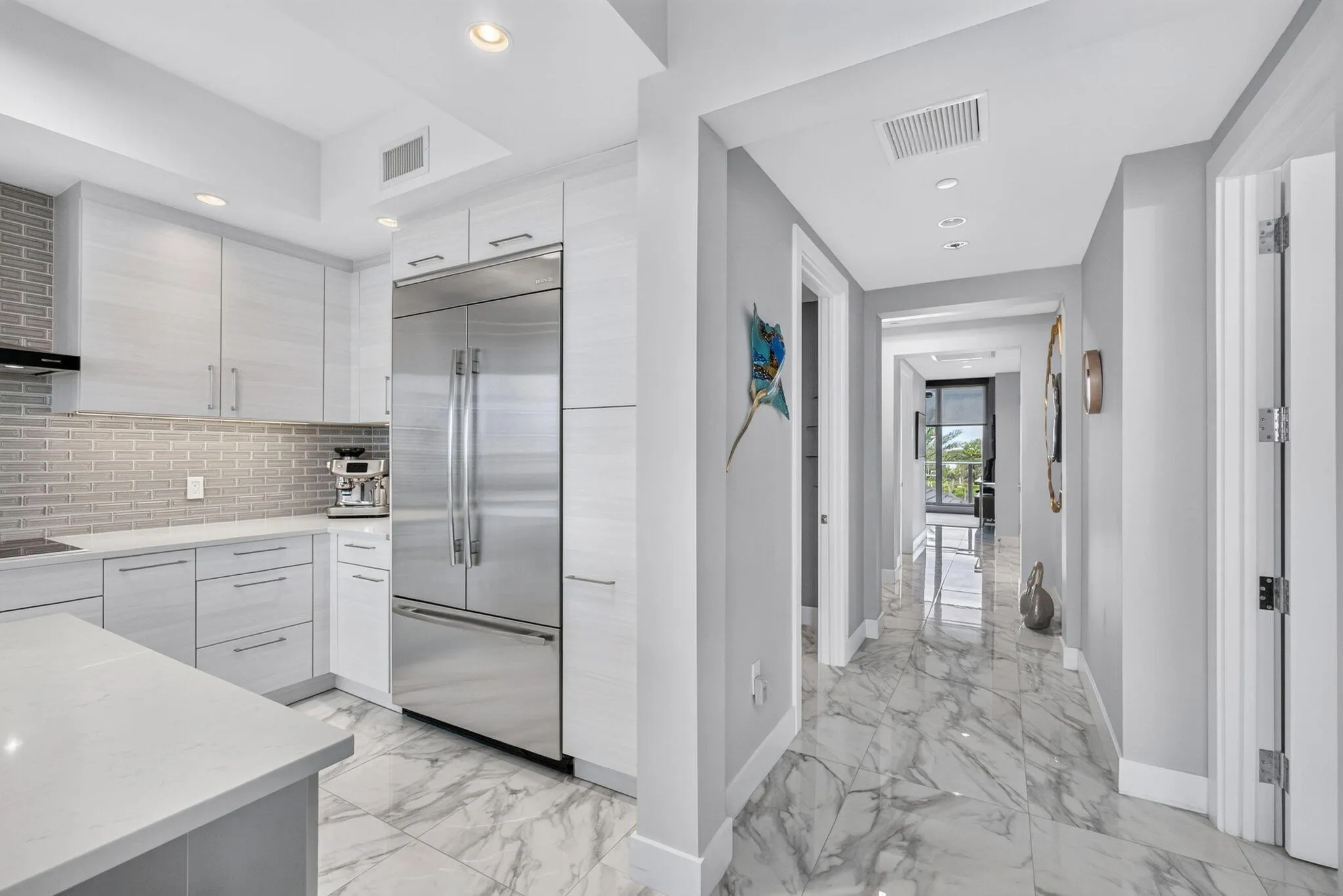 Modern kitchen featuring light-toned cabinetry, stainless steel appliances, and a tiled backsplash