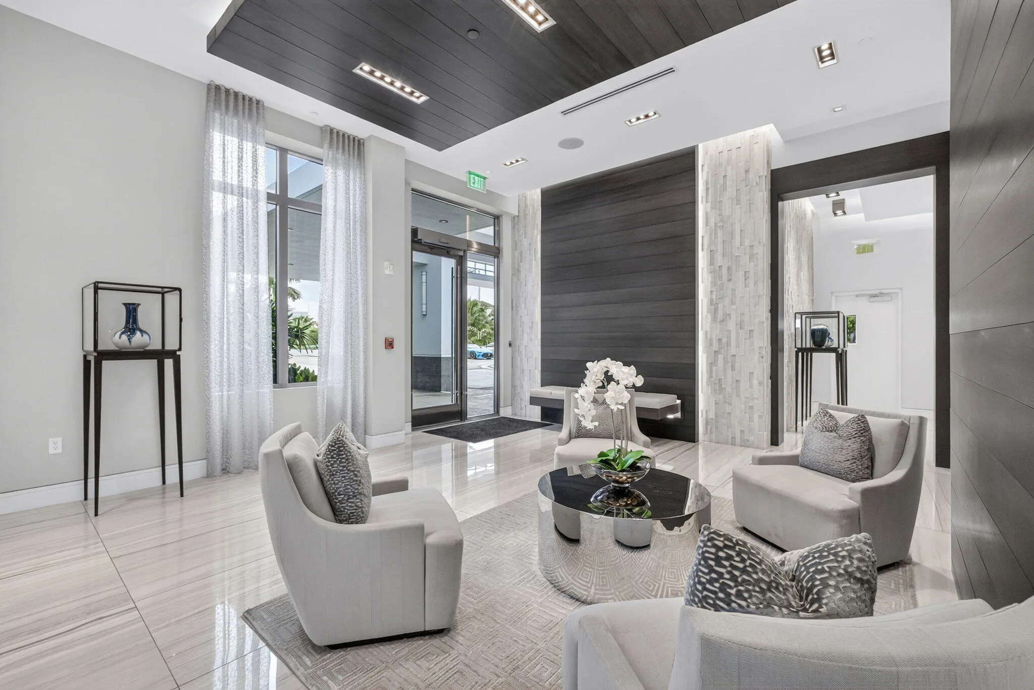 This stunning lobby featuring large format tile flooring, a wood-paneled ceiling with recessed lighting, full-height windows, a textured accent wall, and wood-paneled walls will be the envy of both friends & family.