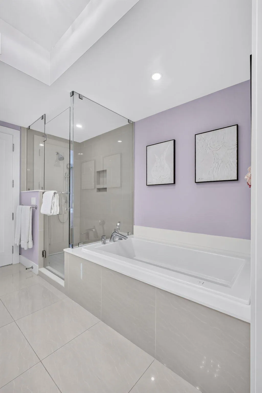 Walk-in shower with glass enclosure, built-in soaking tub with tile surround, recessed lighting, and large format floor tiling