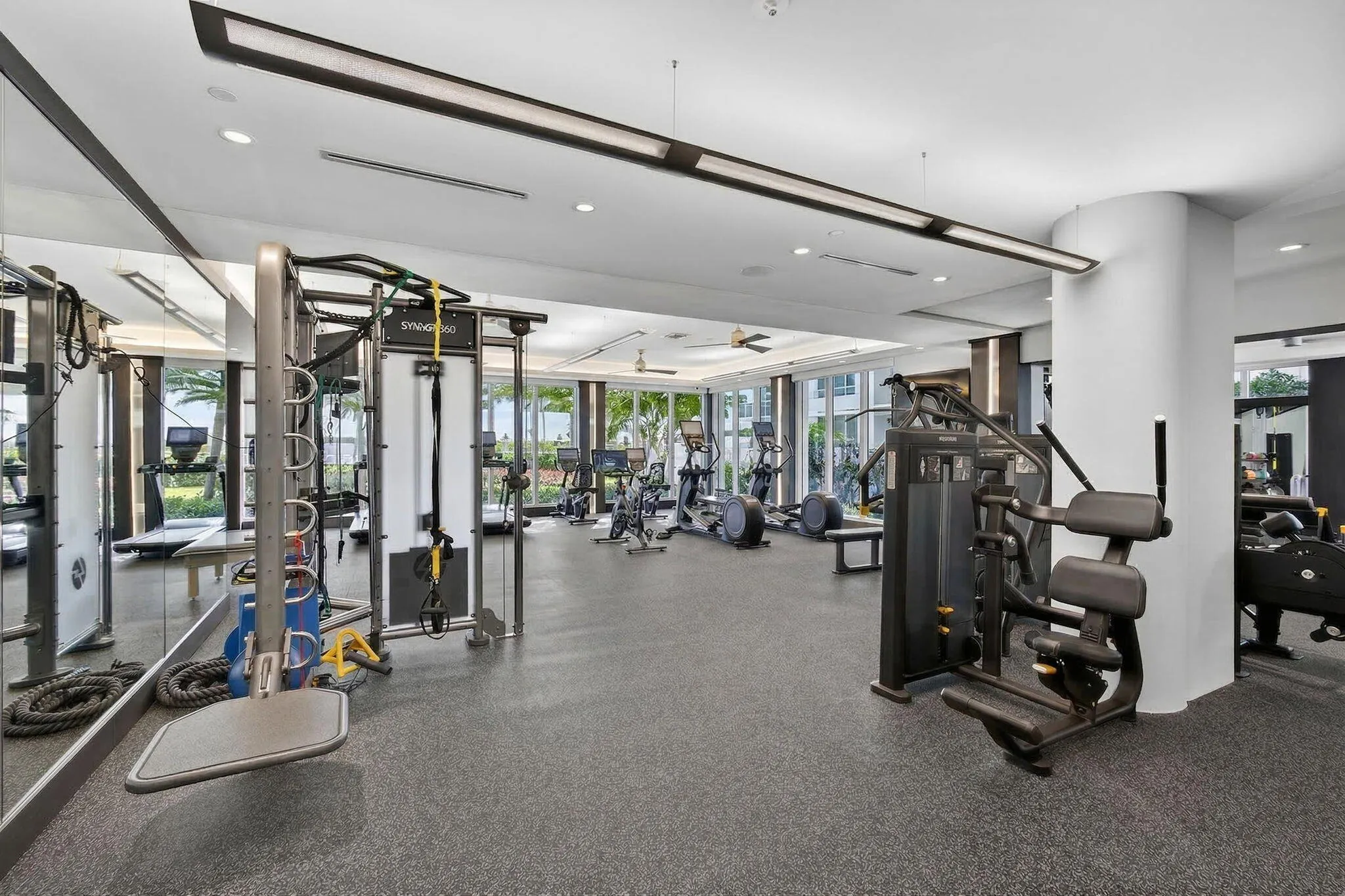 Fitness area featuring a rubberized floor, mirrored wall, recessed lighting, and expansive windows