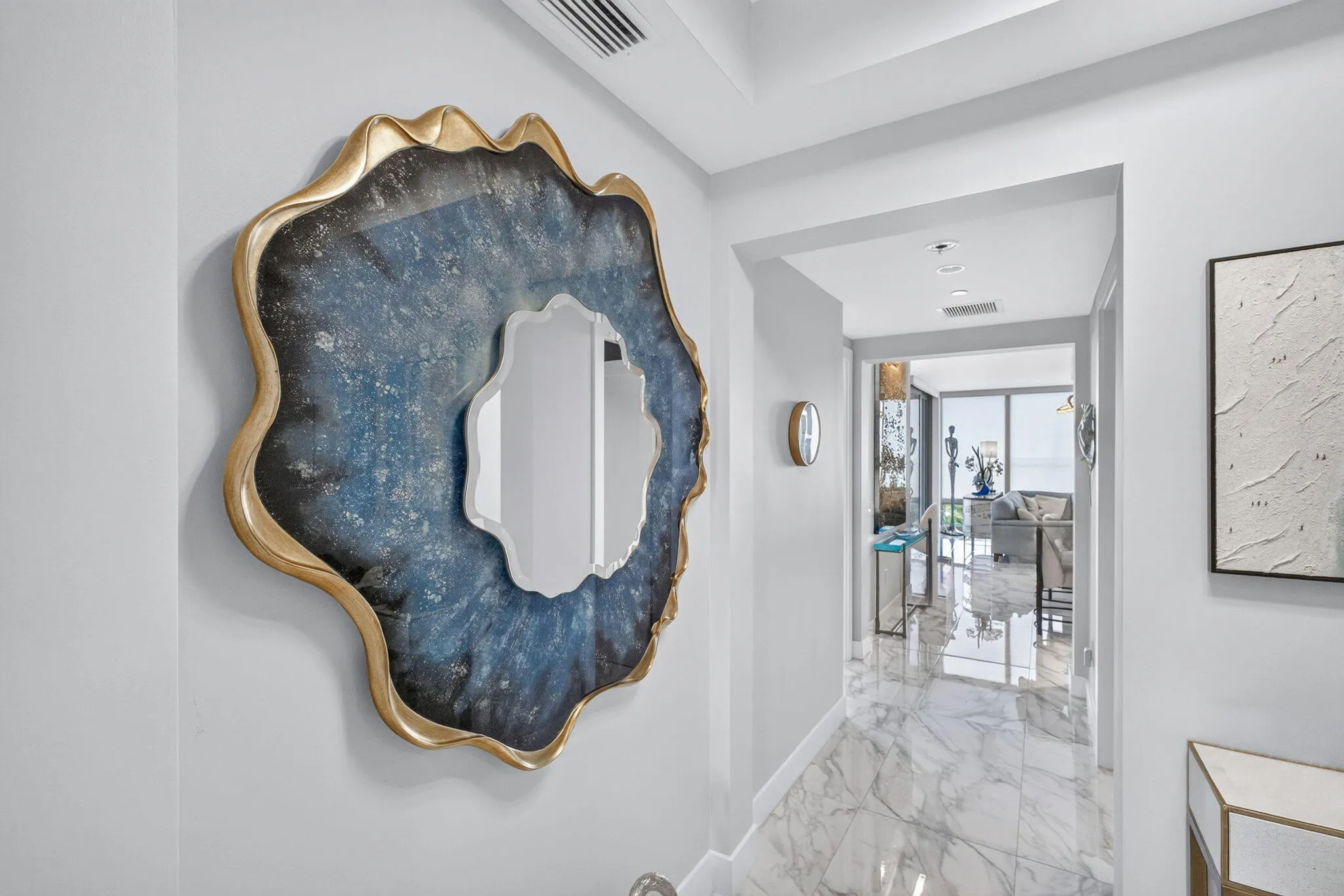 Hallway featuring marble-finish flooring, recessed lighting, and an archway leading to the East wing or the West wing of the home.